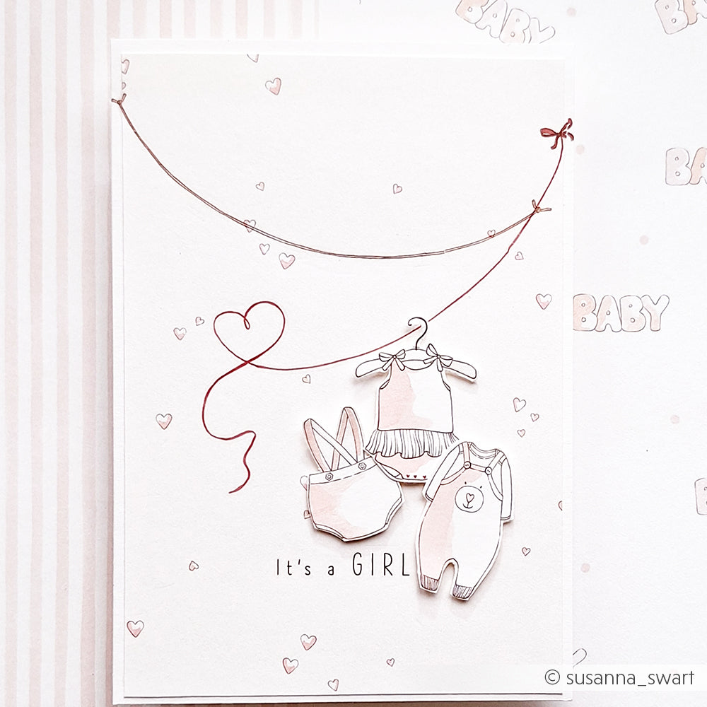 Flachdruck von Babymädchenkleidung auf einer "It's a GIRL"-Karte mit Herz-Akzenten, mit Alexandra Renke zartes Designpapier Herzchen rosa-perfekt für charmante Papierprojekte.