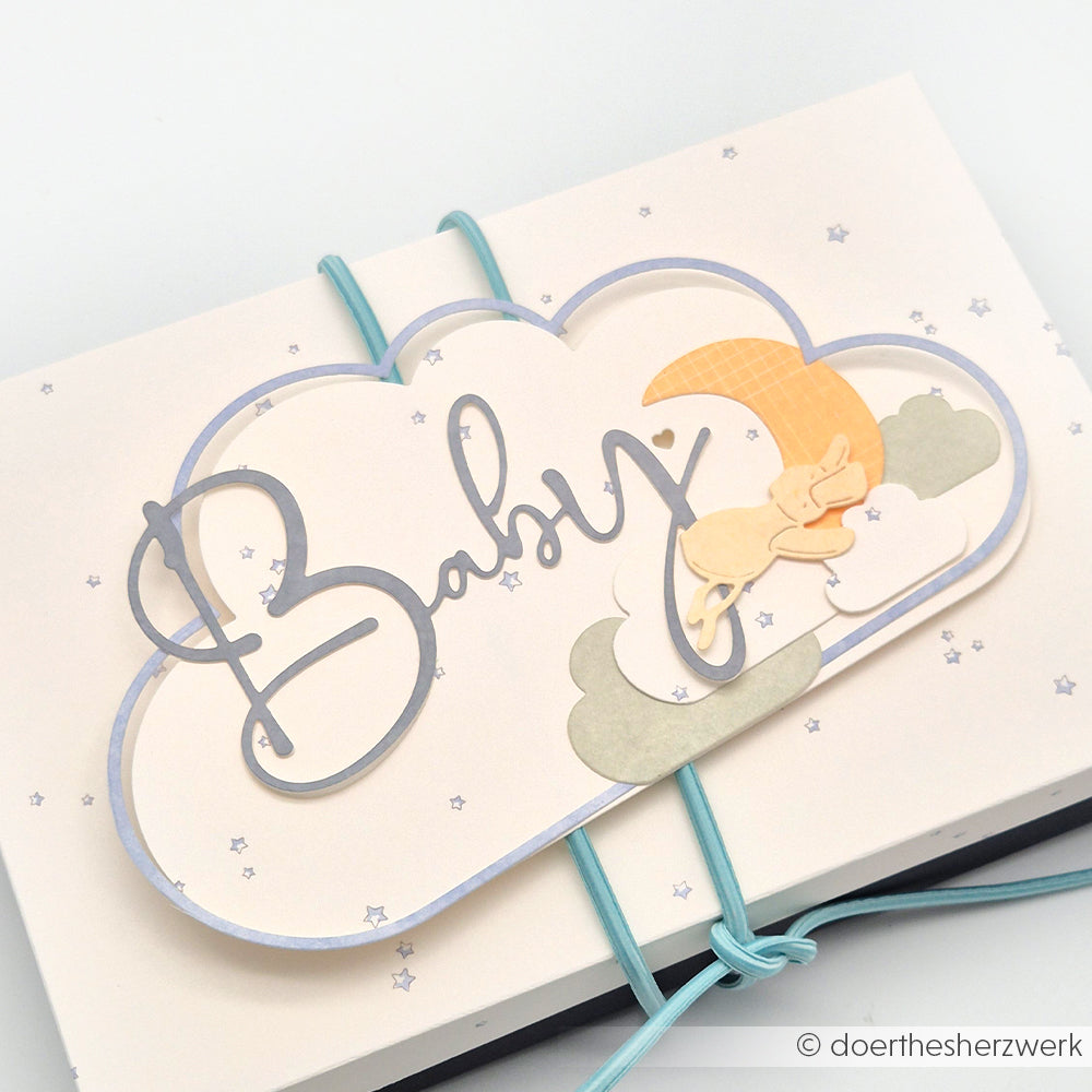 Wolkenförmige Karte von Alexandra Renke mit "Baby"-Text, Sternen und einem schlafenden Hasen auf Wolken und einem gelben Mond - ideal zum Papierbasteln oder Buchbinden mit Designpapier Sternenhimmel hellblau.