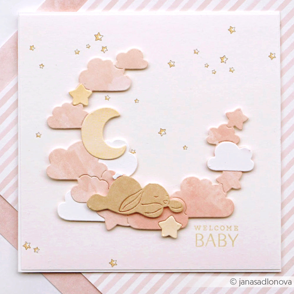 Rosa- und cremefarbene Babykarte von Alexandra Renke mit einem schlafenden Häschen, Wolken, Mond, Sternenhimmel, hochwertigem Designpapier und den Worten "Welcome Baby".