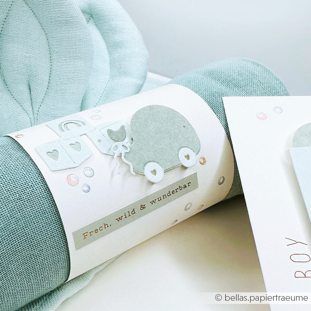 Das hellblaue Designpapier von Alexandra Renke zeigt eine Karte mit einem Kinderwagen, Herzen und "Frech, wild & wunderbar" - ideal für kreative Grußkarten oder Papierprojekte.