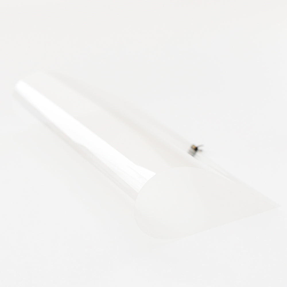 Ein klares, flexibles Transparentpapier von Alexandra Renke, gerollt zu einem losen Zylinder auf weißem Hintergrund - perfekt für Bastelprojekte und zum Bedrucken für personalisierte Bastelarbeiten.