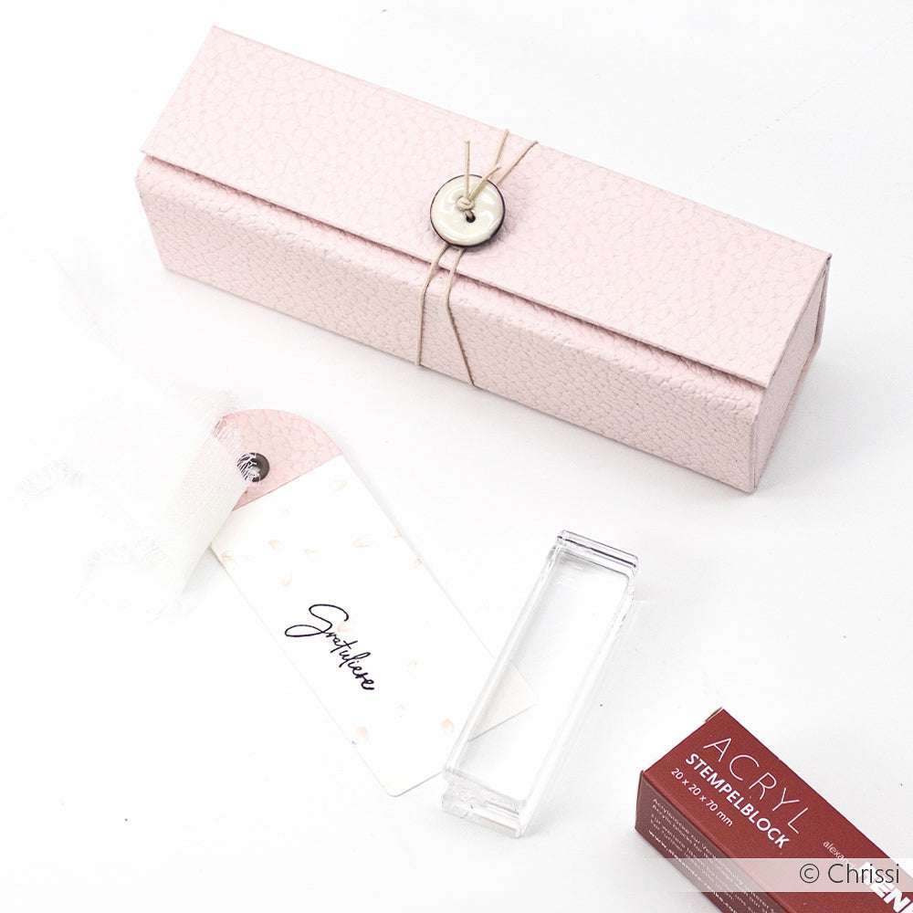 Die ☆ rosa strukturierte Geschenkbox mit Knopfverschluss, FSC-zertifiziertem 3D-geprägtem Papier, Geschenkanhänger, klarem Acrylblock und rotem ACRY-Stempelblock steht auf einem weißen Hintergrund.