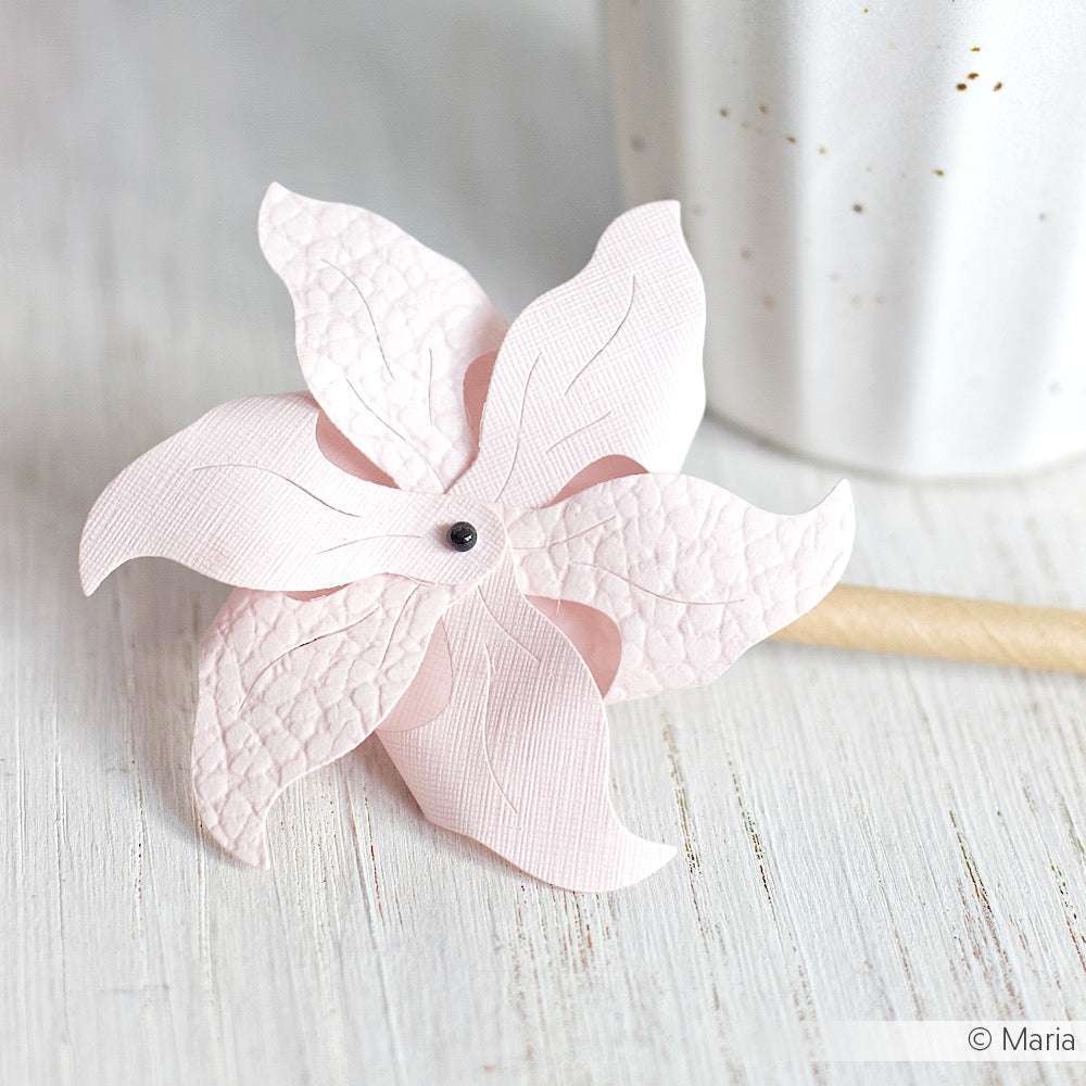 Eine rosafarbene ☆ Cardstock Bubble-Papierblume aus FSC-zertifiziertem 3D-geprägtem Papier steht auf einer weißen Holzfläche neben einer weißen Keramiktasse.