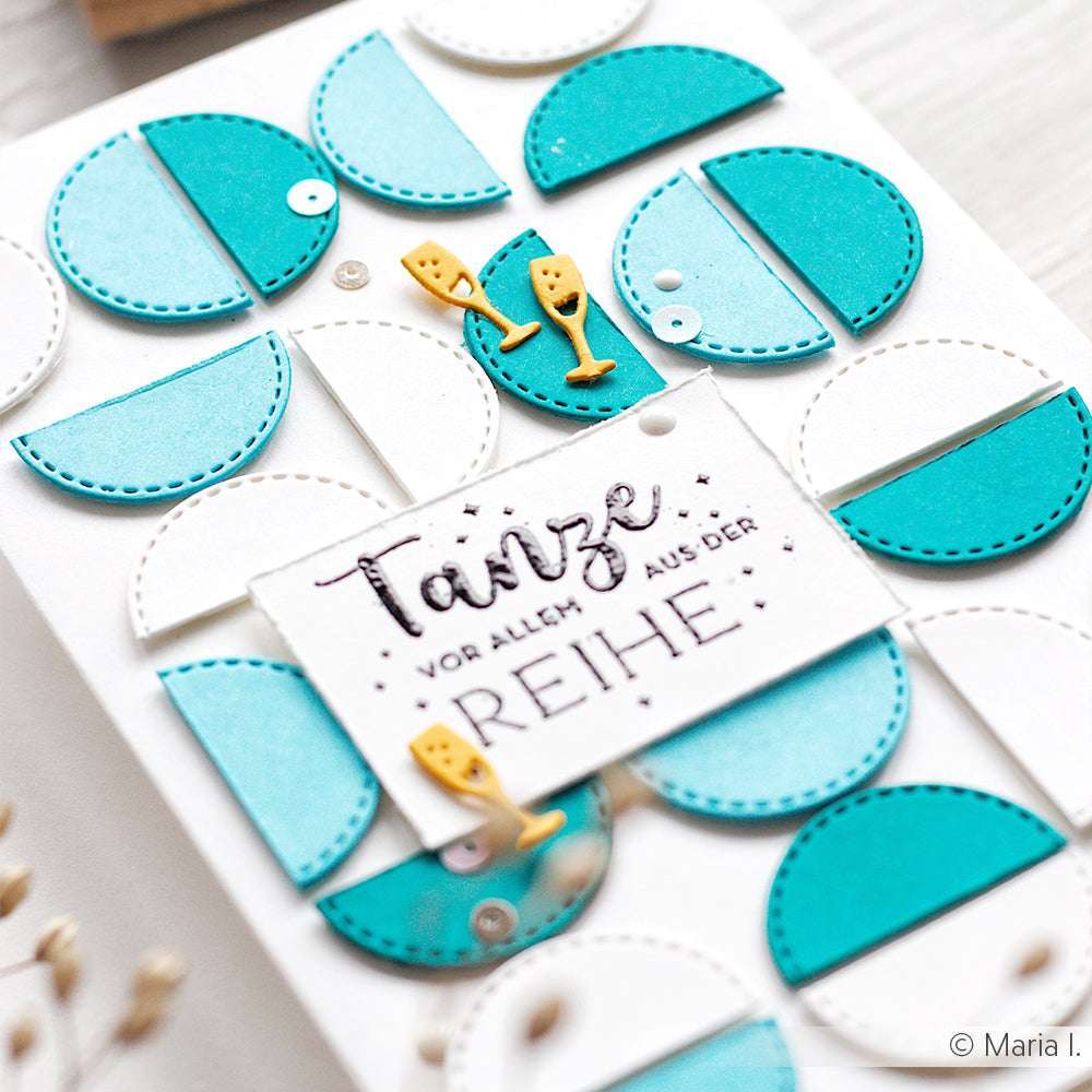 Eine Karte von Alexandra Renke aus 700g/m² Karton mit blauen und blauen Halbkreisen, zwei gelben Sektgläsern und einem deutschen Text in der Mitte der Vorderseite.