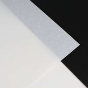 Ein transluzentes Blatt Alexandra Renke Pergamentpapier, das über schwarze und weiße Oberflächen gelegt wird, bietet einen starken Kontrast - perfekt für luxuriöse Verpackungen oder hochwertige Drucke.