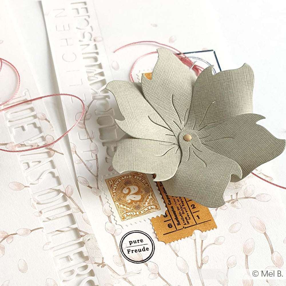 Eine strukturierte Papierblume von ☆, hergestellt aus FSC-zertifiziertem 120g/m² Papier, verziert mit Stempeln, Schnur und gestanzten Buchstaben auf weißem Hintergrund.