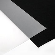 Ein Blatt durchscheinendes Transparentpapier von Alexandra Renke, das häufig für Laternen- oder Windlichter-Basteln verwendet wird, liegt zwischen schwarzen und weißen Blättern auf einer ebenen Fläche.