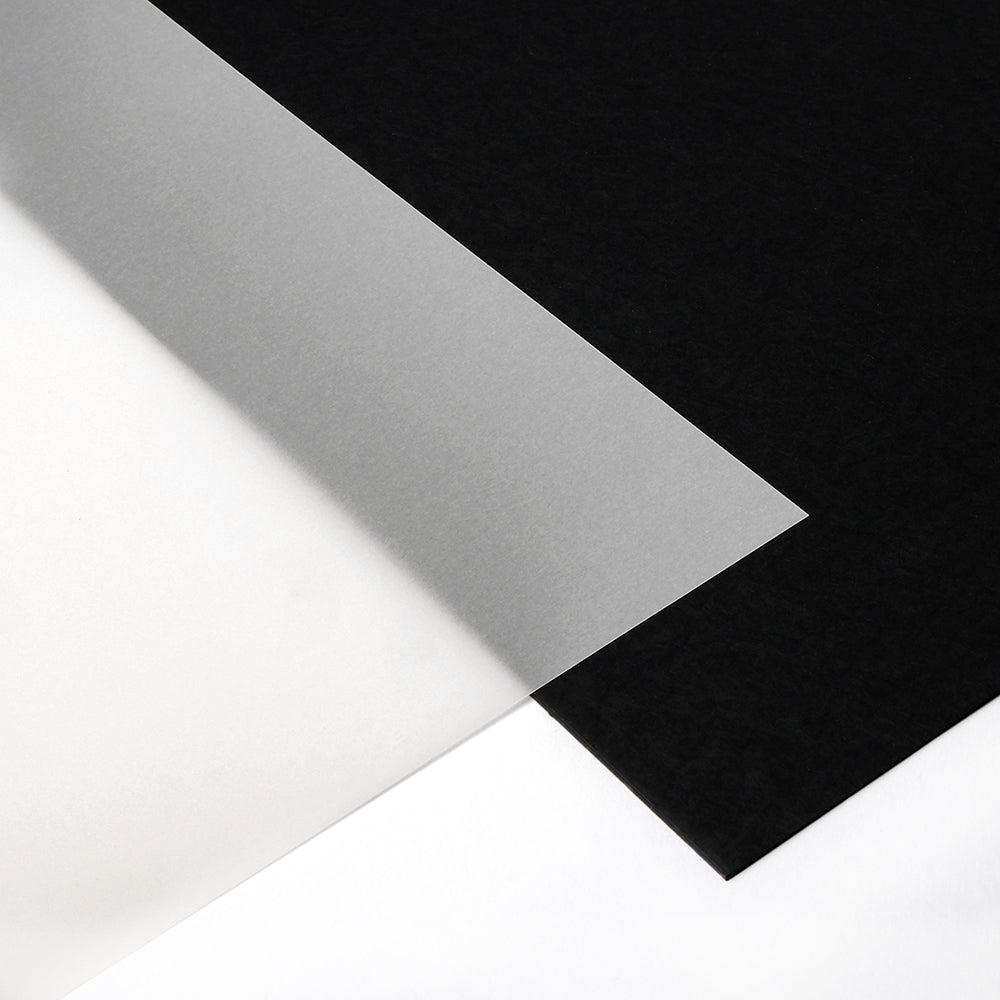 Ein durchsichtiges Blatt Alexandra Renke Transparentpapier wird über schwarzes und weißes Papier gelegt, ideal zum Basteln oder zum Herstellen von Windlichtern.