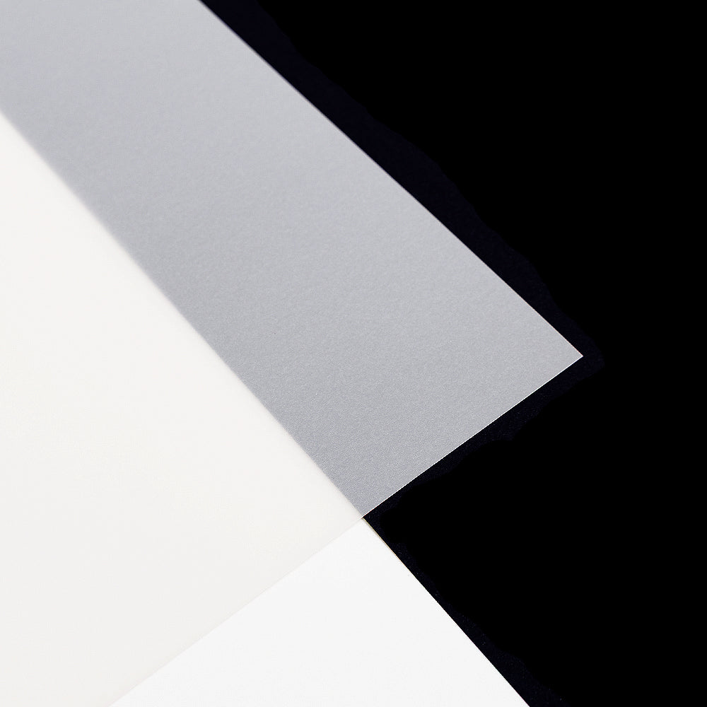 Drei sich überlappende Papierbögen, darunter ein durchscheinendes Transparentpapier im klassischen DIN-A4-Format, sind kunstvoll auf einem schwarzen Hintergrund angeordnet – die perfekte Inspiration für jedes Bastelprojekt.