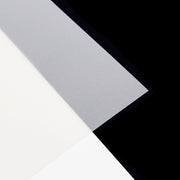 Drei sich überlappende Papierbögen, darunter ein durchscheinendes Transparentpapier im klassischen DIN-A4-Format, sind kunstvoll auf einem schwarzen Hintergrund angeordnet – die perfekte Inspiration für jedes Bastelprojekt.