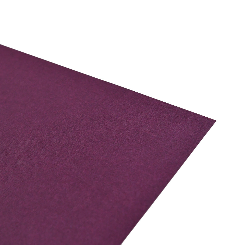 Eine Nahaufnahme eines strukturierten, dunkelvioletten ☆ Spezialpapierbogens mit einer sichtbaren Ecke - perfekt für Buchbinden oder hochwertige Projekte, die ein elegantes Finish erfordern.