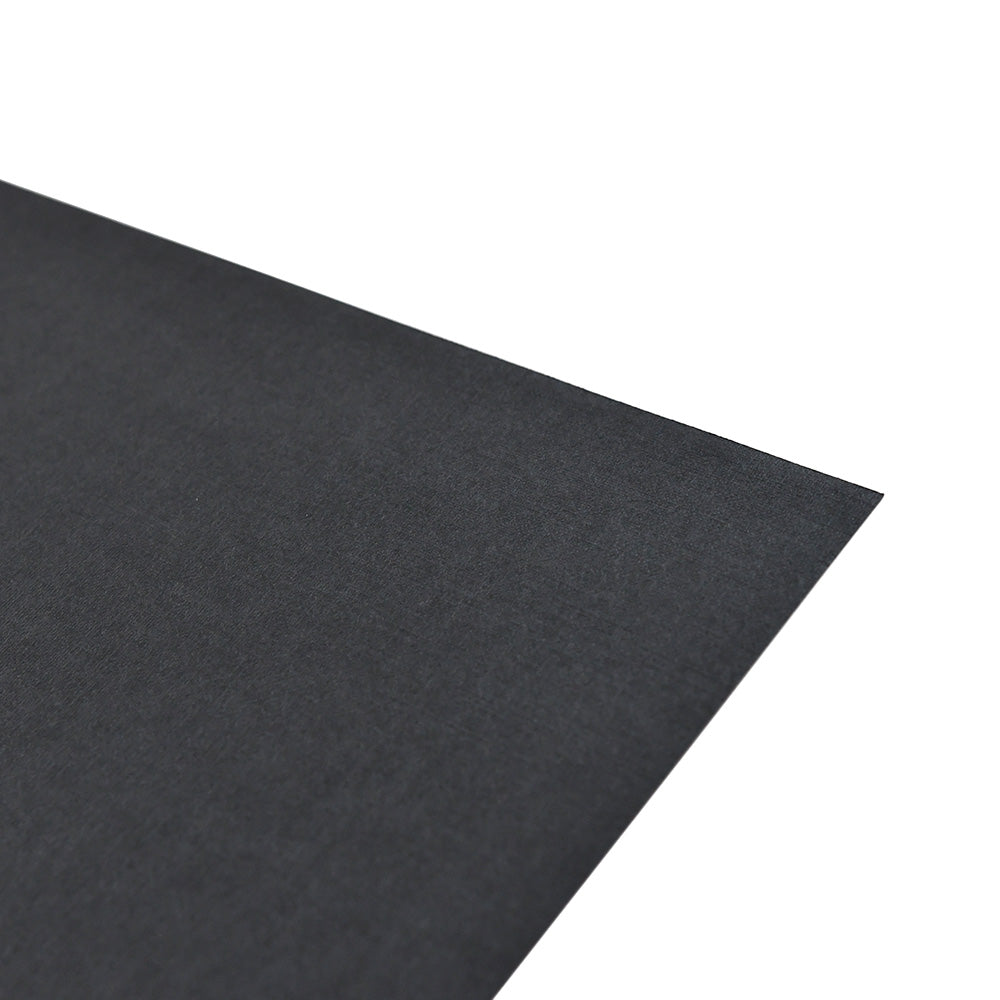 Eine Nahaufnahme der Ecke eines schwarzen ☆ Feinleinen Cardstock Bogens auf weißem Hintergrund.