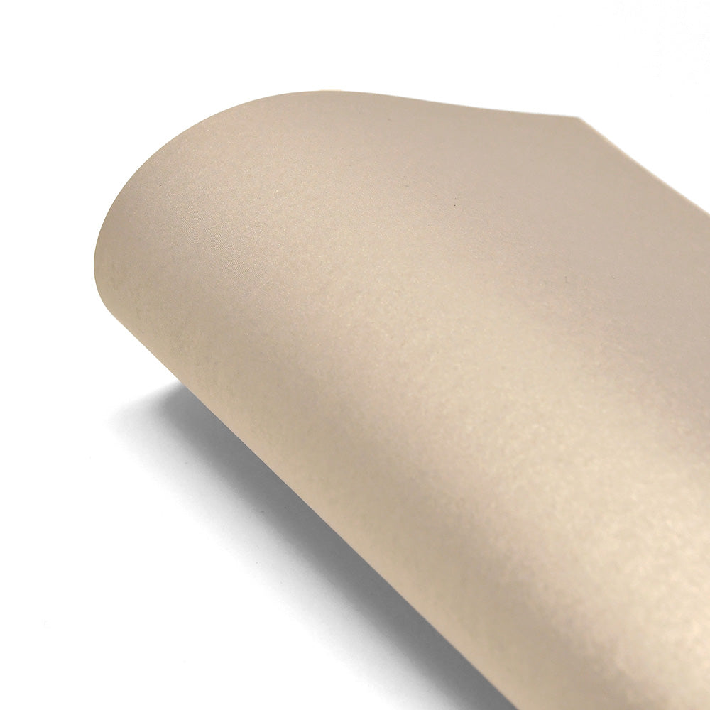 Eine Rolle glattes, hellbeiges ☆ Schimmer-Effekt Papier (310g/m²) wird teilweise auf einer weißen Oberfläche abgerollt, ideal für Papierkunst oder kreative Projekte.