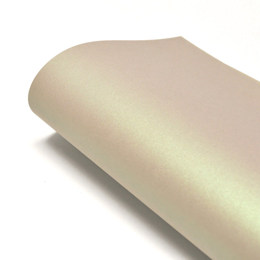 Nahaufnahme eines aufgerollten Bogens von glattem, perlmuttartigem beigem ☆ Schimmer-Effekt Papier (310g/m²) auf weißem Hintergrund.