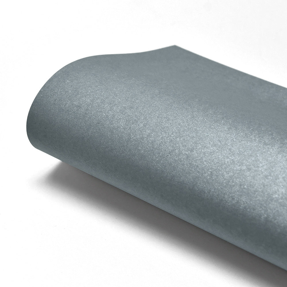 Ein gerollter Bogen ☆ Schimmer-Effekt Papier, silber-metallic, 310g/m², auf weißem Hintergrund - ideal für raffinierte Papierkunstprojekte.