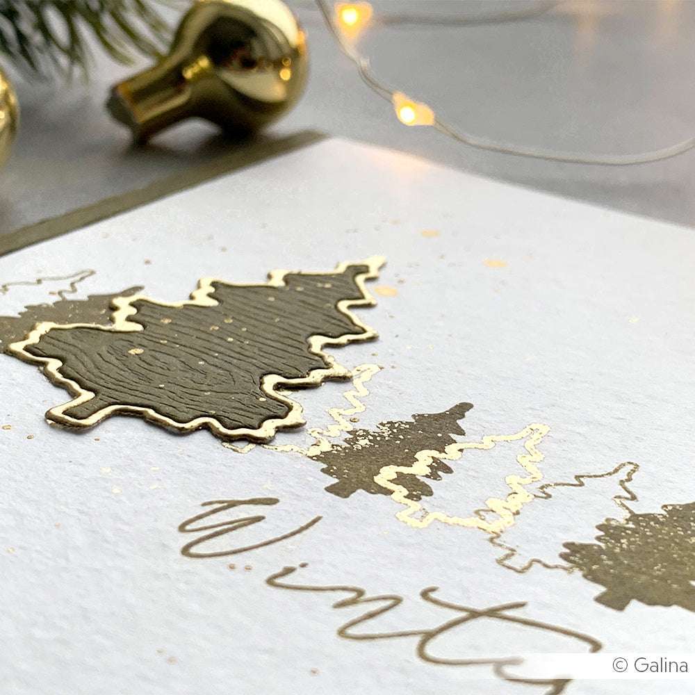 Nahaufnahme einer ☆ Weihnachtskarte mit Weihnachtsbäumen aus Goldfolie und "Winter" in eleganter Schrift, gedruckt auf FSC-zertifiziertem 300g/m² Papier für eine hochwertige Haptik.