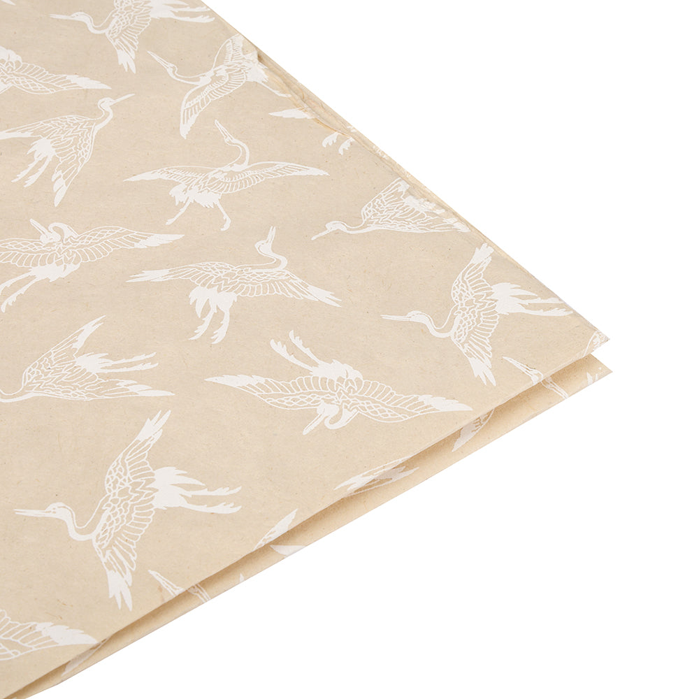 ☆ Nepalpapier in Beige mit weißen Kranich-Illustrationen, handgeschöpft und an der Ecke gefaltet - nachhaltiges Geschenkpapier auf weißem Hintergrund.