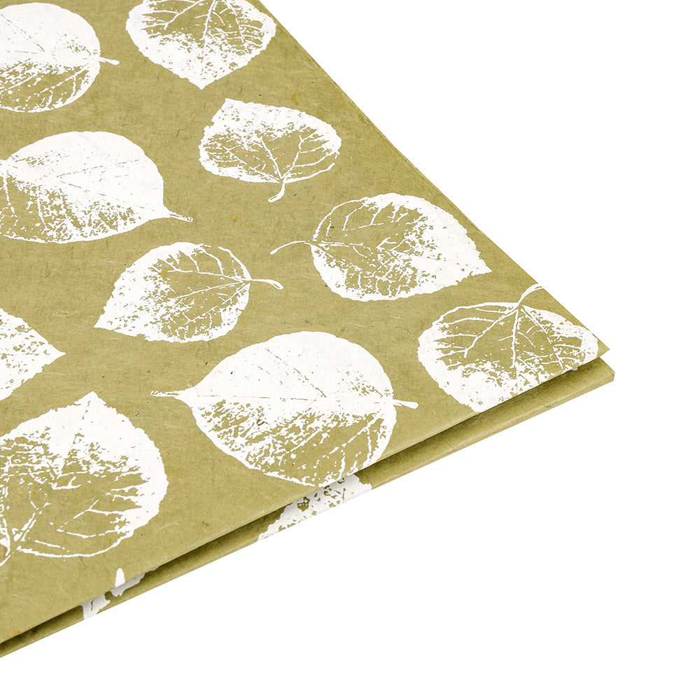 Olivgrünes Nepalpapier mit weißem Blattdruck von ☆ - nachhaltig, stilvoll und teilweise gefaltet auf weißem Hintergrund. Perfekt als Geschenkpapier für umweltbewusste Anlässe.