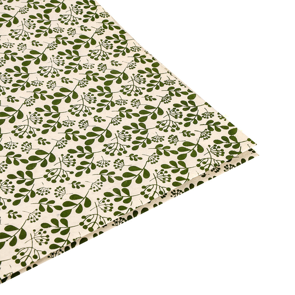 Beigefarbener Stoff von ☆ mit einem sich wiederholenden grünen Blatt- und Zweigmuster, teilweise auf Weiß abgebildet - ideal zum Einpacken von Geschenken oder in Kombination mit nachhaltigem Papier für eine umweltfreundliche Präsentation.