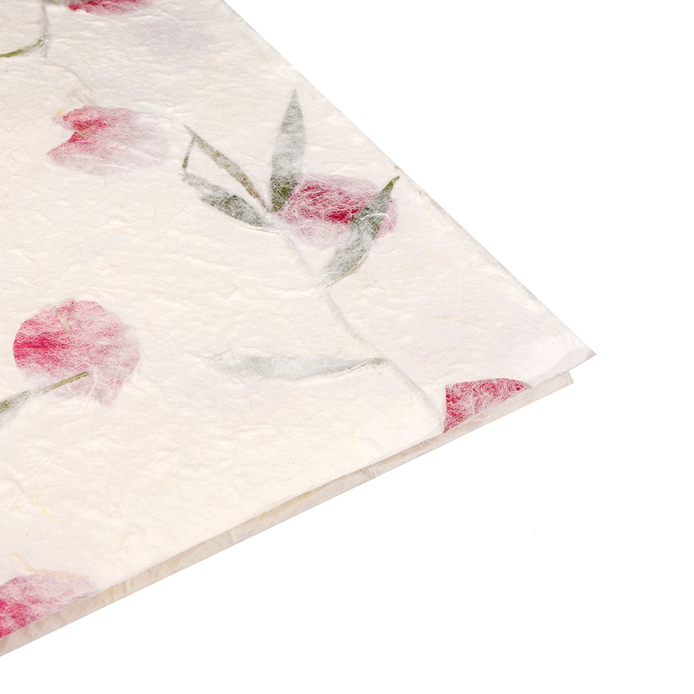 Nahaufnahme des strukturierten weißen Maulbeerpapiers von ☆ mit gepressten rosa Blüten und grünen Blättern - ideal für einzigartige Geschenkverpackungen.