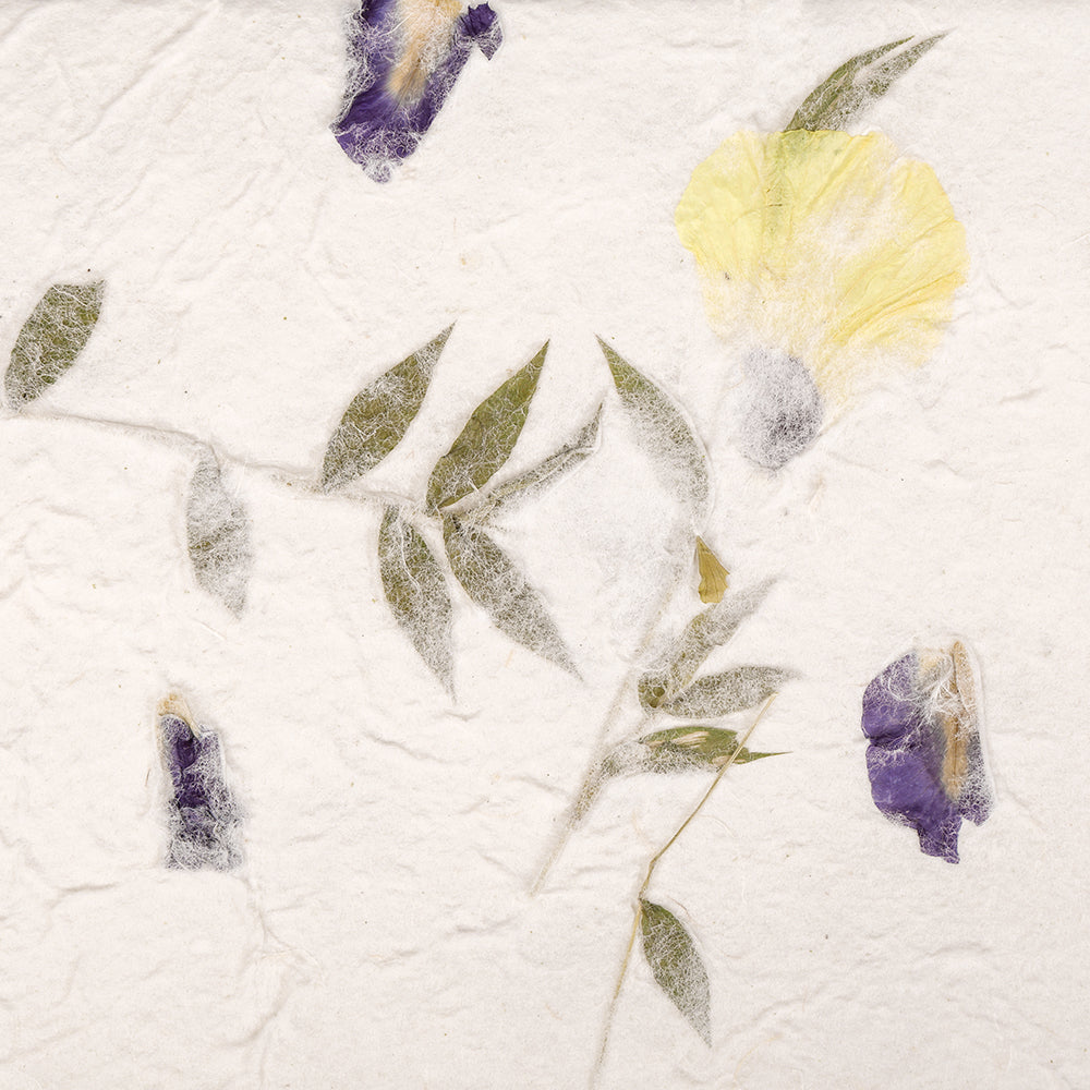 ☆ Handgeschöpftes Papier mit grünen Blättern sowie gepressten lila und gelben Blüten auf weißer Textur - perfekt für Geschenkverpackungen oder kreative Projekte.