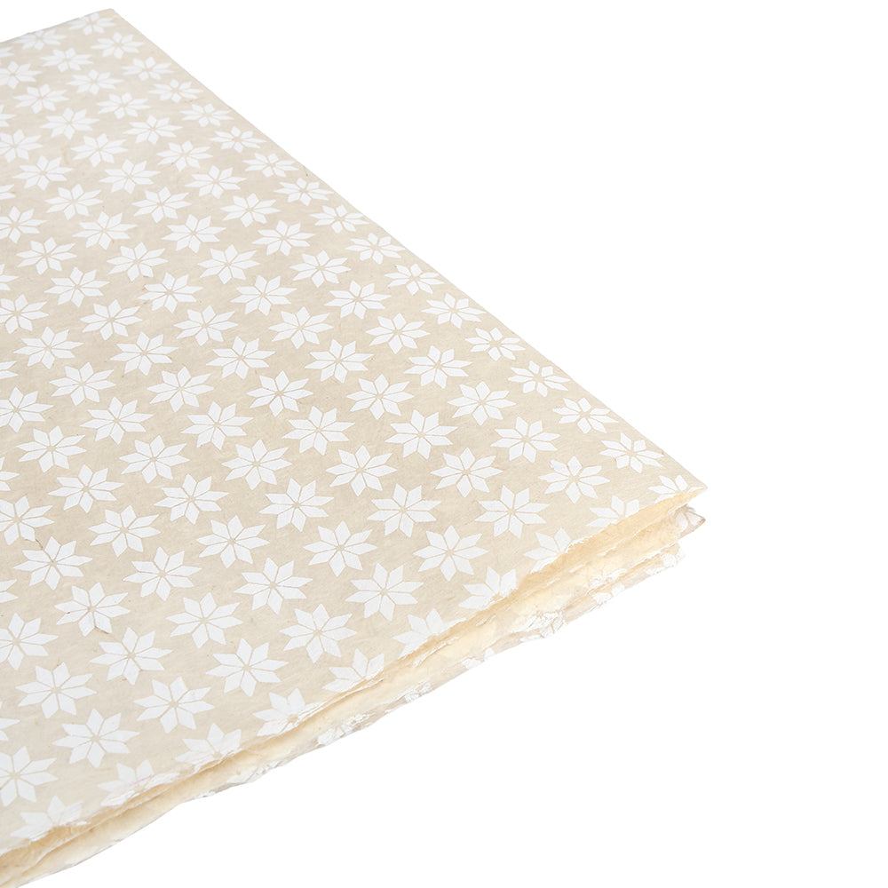 ☆ beigefarbene Nepalpapierbögen mit einem sich wiederholenden weißen Stern- oder Blumenmuster, ideal für nachhaltige Geschenkverpackungen, gestapelt auf weißem Hintergrund.