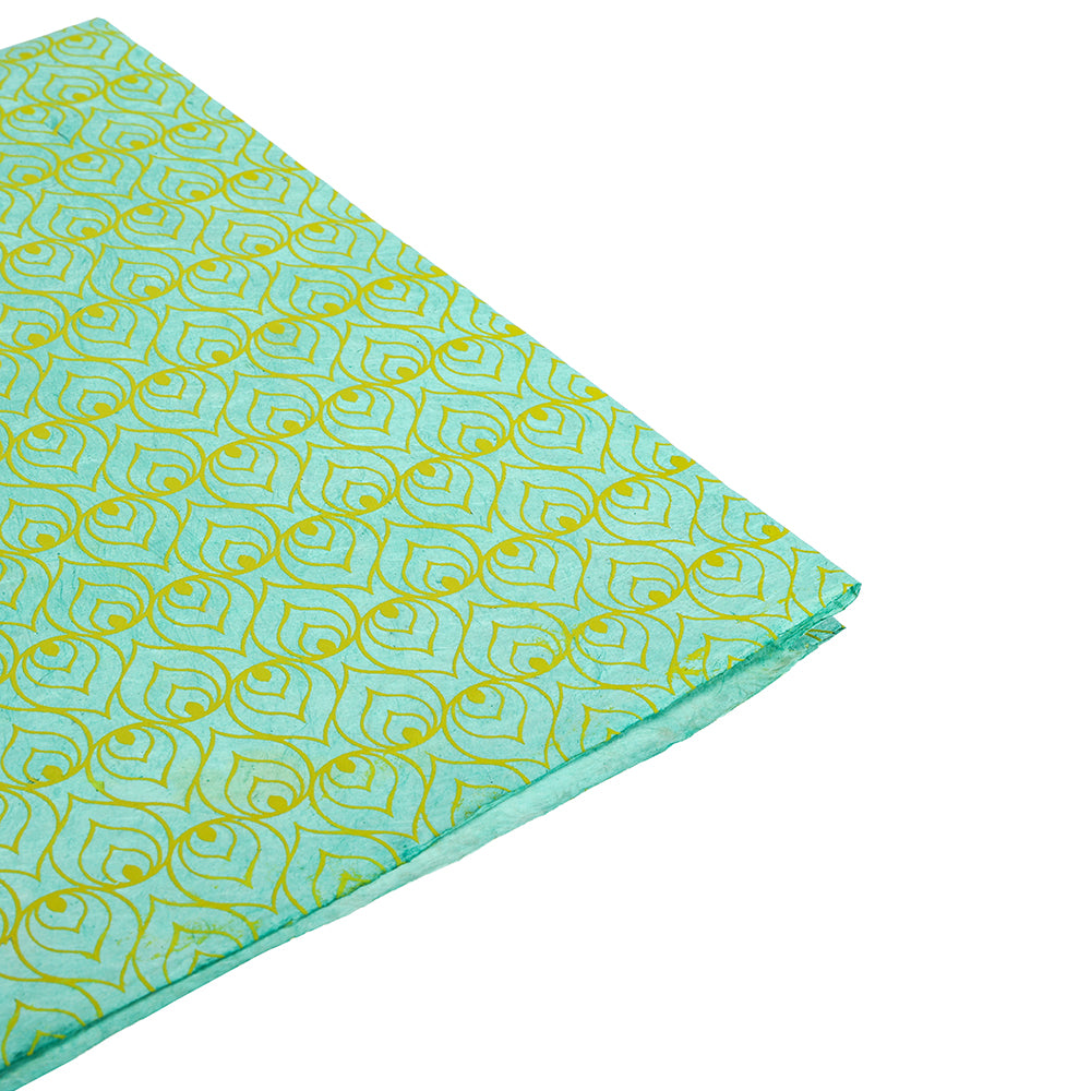 Aquablauer Stoff mit einem sich wiederholenden gelben Paisleymuster, sauber auf weiß gefaltet - erinnert an Nepalpapier blau von ☆, ideal als nachhaltige Geschenkverpackung oder für kreative Projekte.