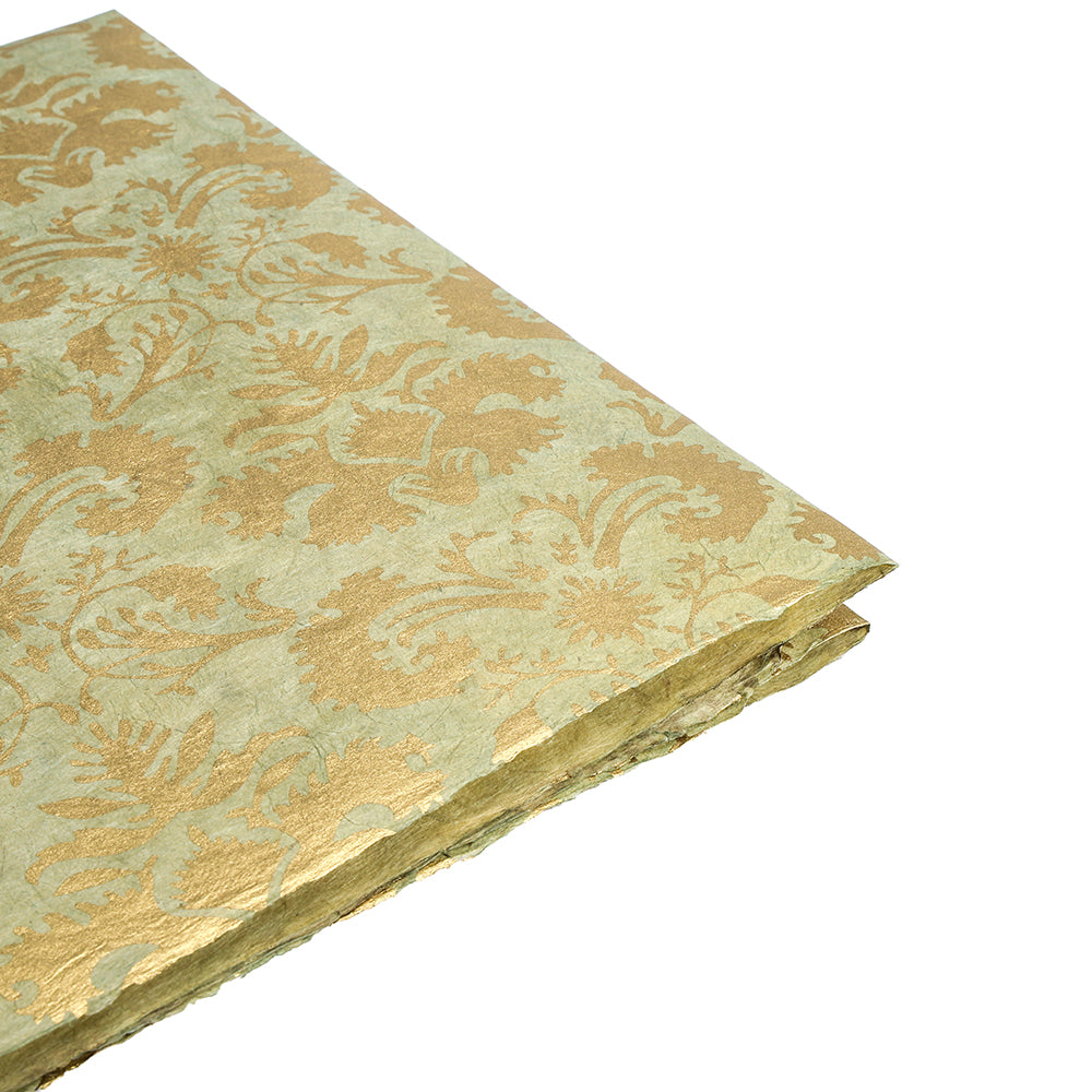 Ein gefaltetes Blatt ☆ Nepalpapier mit einem goldfarbenen Muster ist auf einem weißen Hintergrund abgebildet.