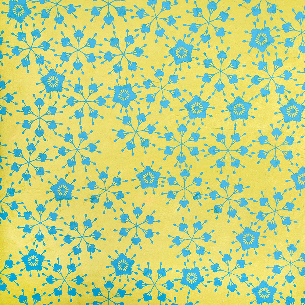 Ein blaues, florales, geometrisches Muster auf gelbem Hintergrund bildet ein symmetrisches, sich wiederholendes, dekoratives Design - ideal für Geschenkverpackungen. Hergestellt aus nachhaltigem Papier von ☆.