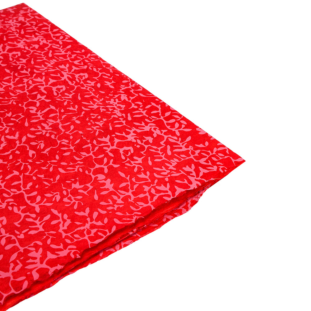Gefalteter roter Stoff von ☆ mit abstraktem rosa Blattmuster auf weißem Grund, der an elegantes Geschenkpapier oder handgeschöpftes Papier aus Nepal erinnert.