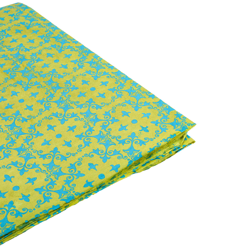 Gefalteter grüner und blauer Stoff mit verschlungenen floralen und geometrischen Mustern auf weißem Grund, der an das exquisite Design von ☆ Nepalpapier Geschenkpapier erinnert.