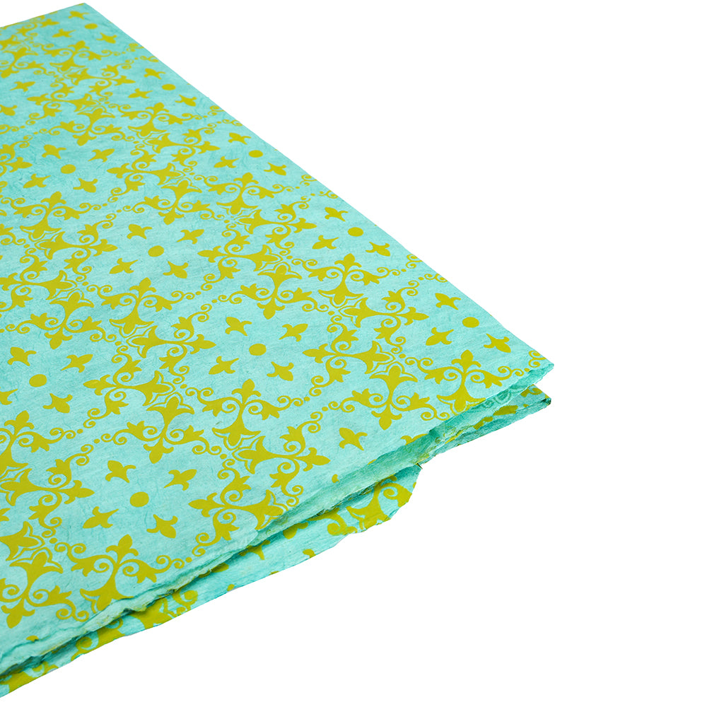 Gefalteter türkisfarbener Stoff von ☆ mit einem gelben Blumen- und Wirbelmuster auf weißem Hintergrund - ideal als nachhaltiges Papier oder einzigartiges Geschenkpapier.