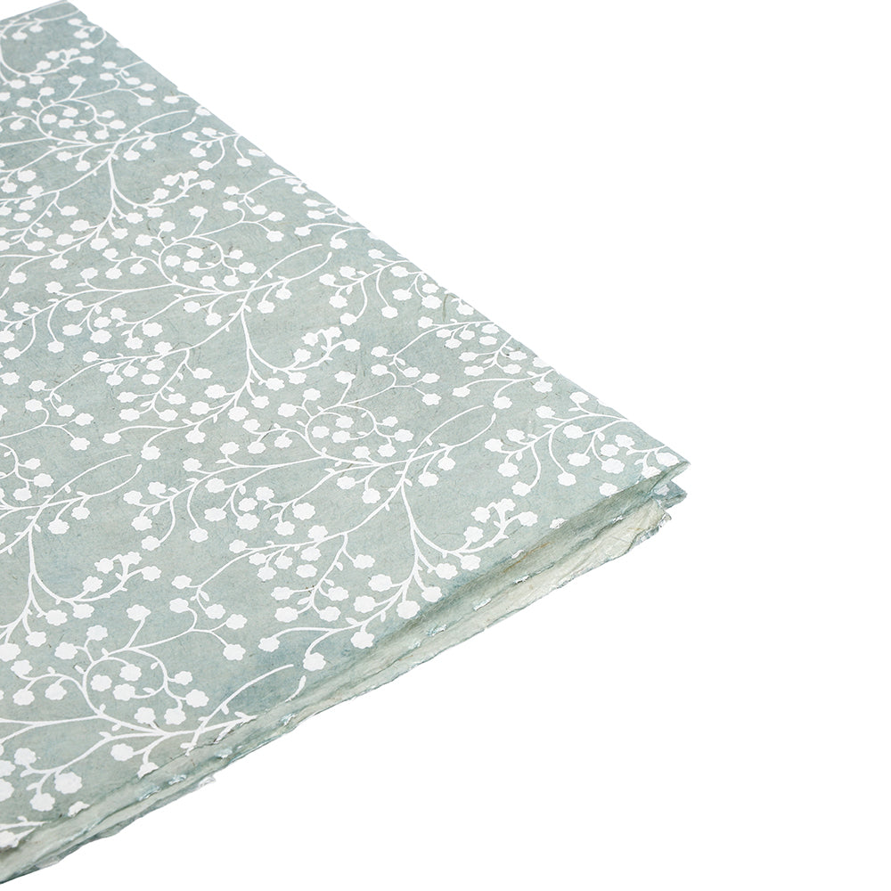 ☆ gefaltetes hellgrünes Nepalpapier mit weißem Blumenrankenmuster auf weißem Hintergrund - das perfekte nachhaltige Geschenkpapier für besondere Anlässe.
