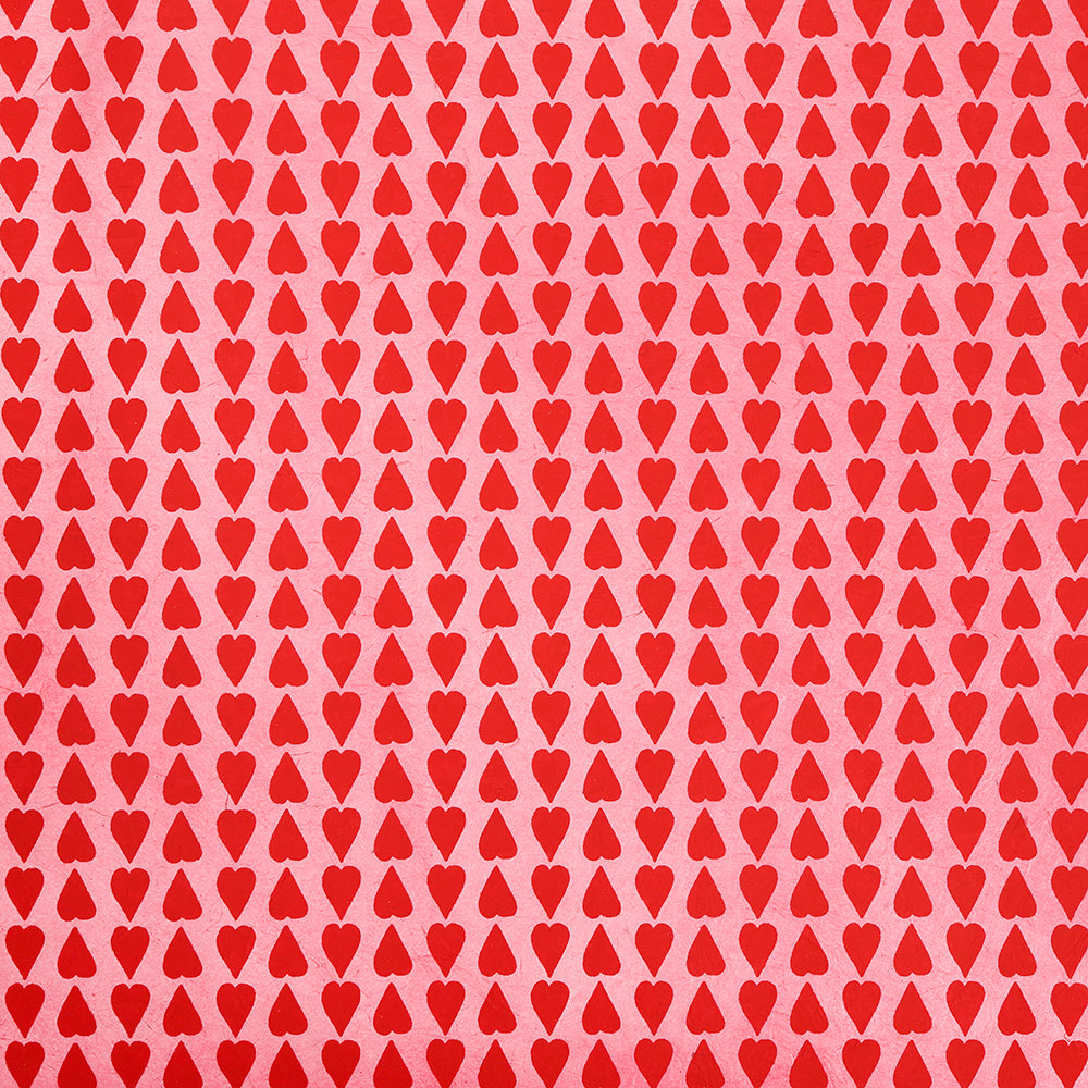 Ein bezauberndes Muster aus gleichmäßig verteilten roten Herzen auf rosafarbenem Hintergrund von ☆, das ein sich wiederholendes Design zum Thema Liebe schafft - ideal für Geschenkverpackungen oder Verpackungen mit nachhaltigem Papier.