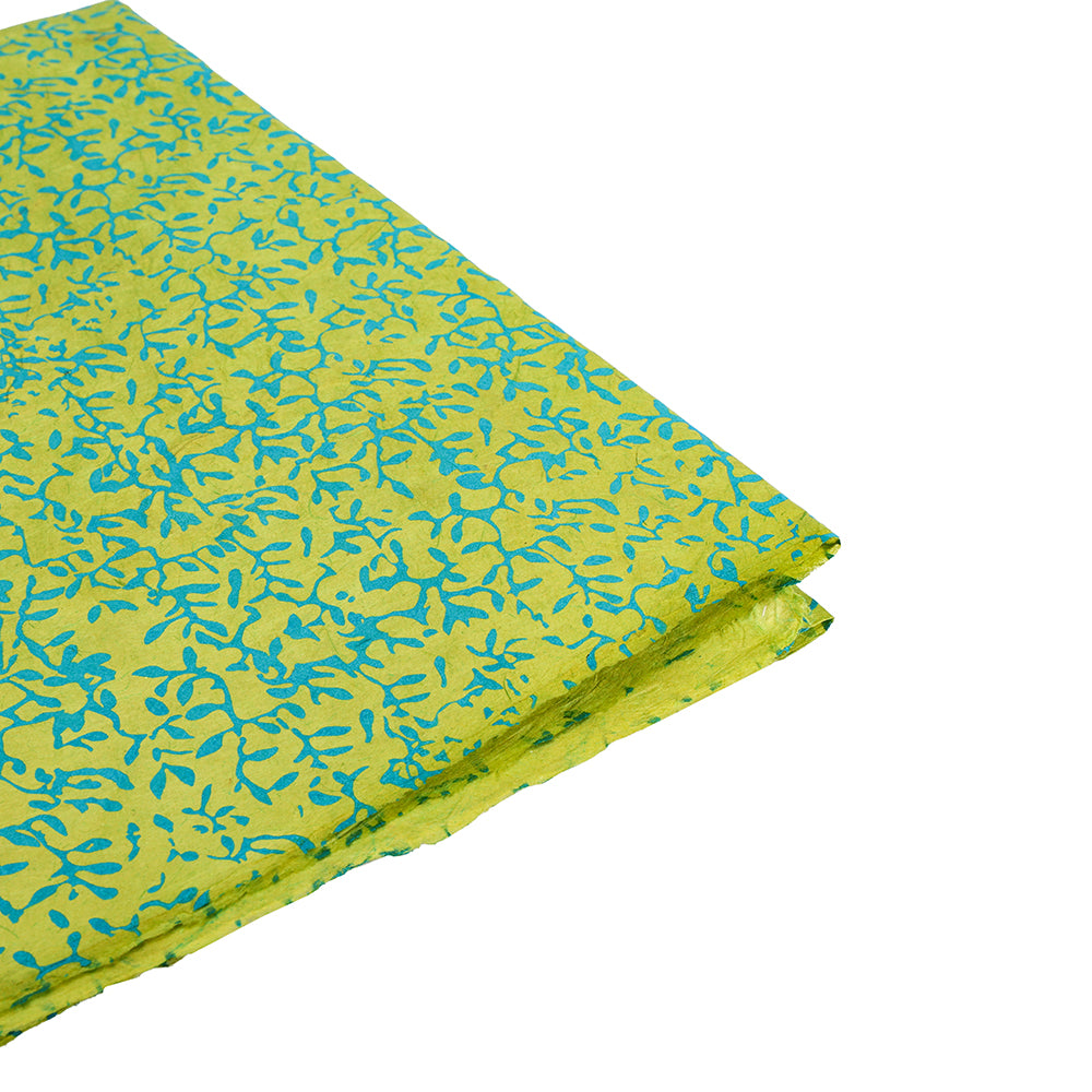 Gefalteter grüner Stoff mit blauem abstraktem Blattmuster von ☆, abgebildet in der Seitenansicht auf Weiß - ideal als umweltfreundliche Geschenkverpackung oder gepaart mit nachhaltigem Papier für besondere Geschenke.