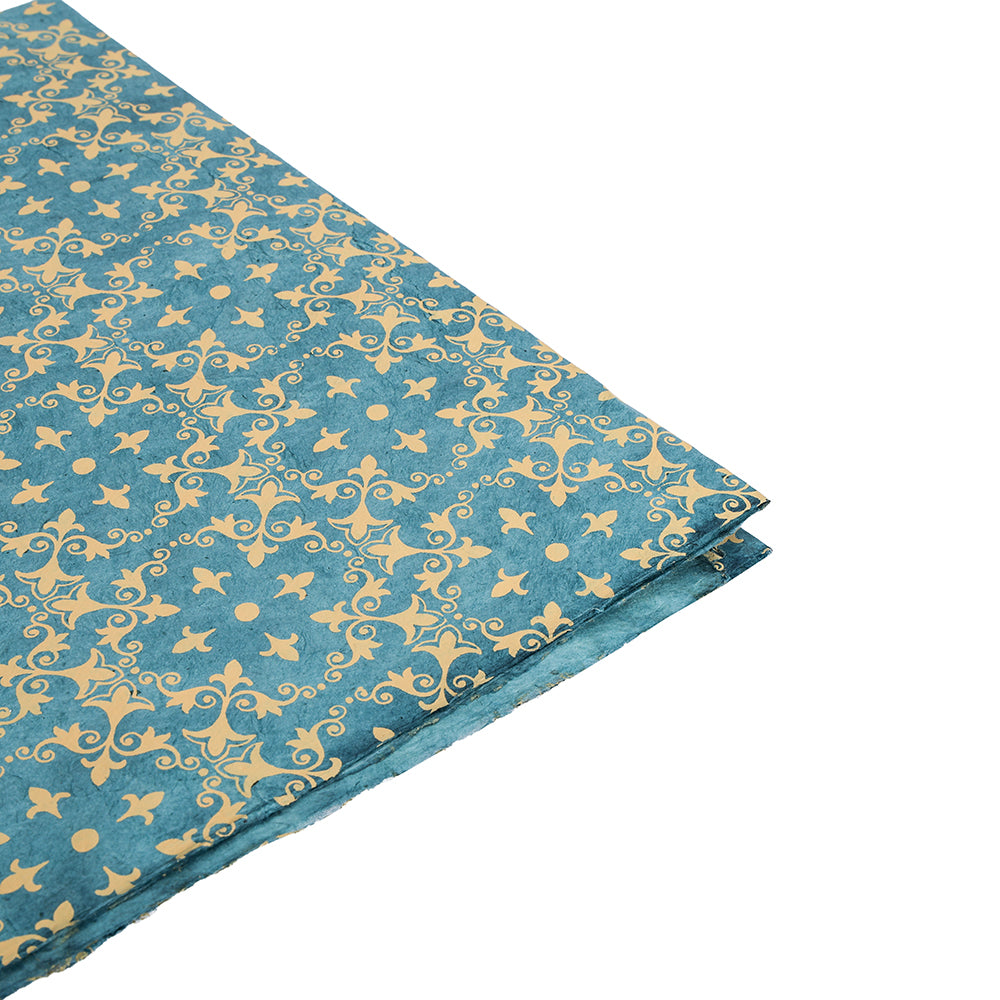 Tealfarbenes Nepalpapier von ☆ mit goldenem Blumen- und geometrischem Muster, hier gefaltet auf Weiß - perfekt als nachhaltiges Papier für besondere Geschenkpapier-Ideen.
