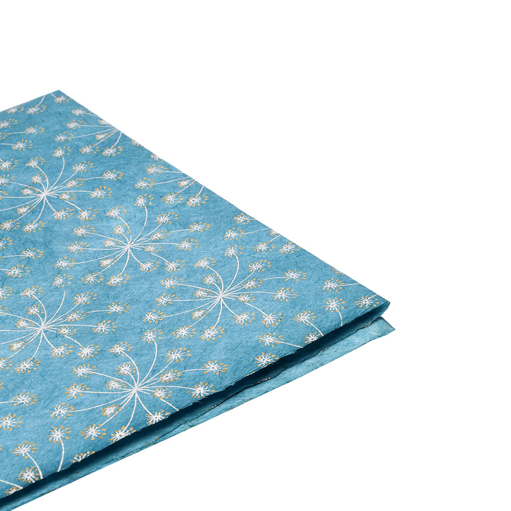 ☆ gefaltetes blaues Nepalpapier mit weißem und goldenem Blumenmuster - nachhaltig, stilvoll und perfekt zum Verpacken von Geschenken. Präsentiert auf weißem Hintergrund.