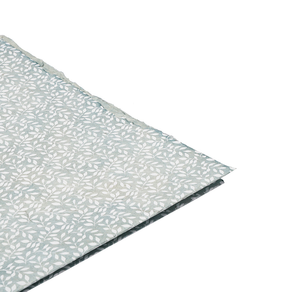 Ein Blatt hellblaues Nepalpapier von ☆ mit zartem weißem Blattmuster, ideal für Geschenkverpackungen, abgebildet auf weißem Hintergrund.