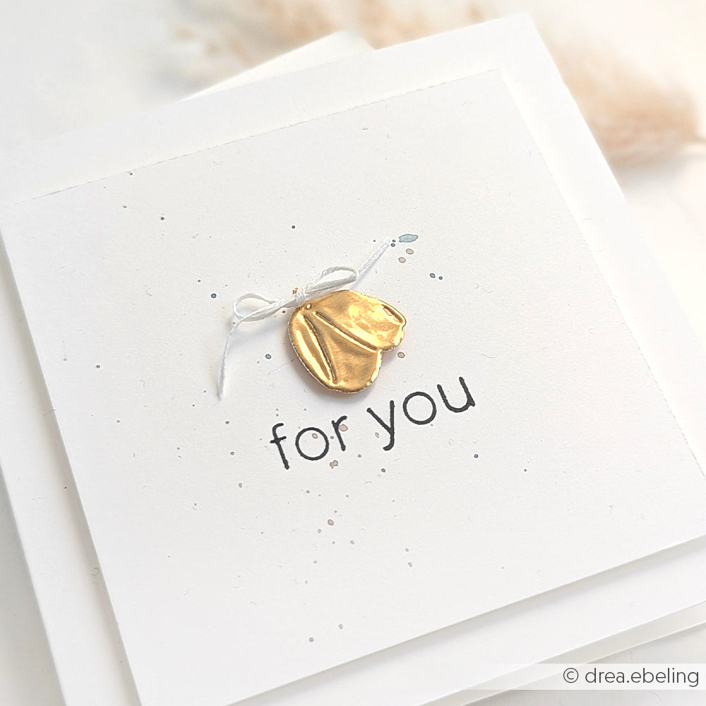 Eine weiße Karte von Alexandra Renke mit einem goldenen Glückskeks und einer Schleife mit goldenen Akzenten und einem darunter gedruckten "Für Sie" - perfekt für Bastelarbeiten.