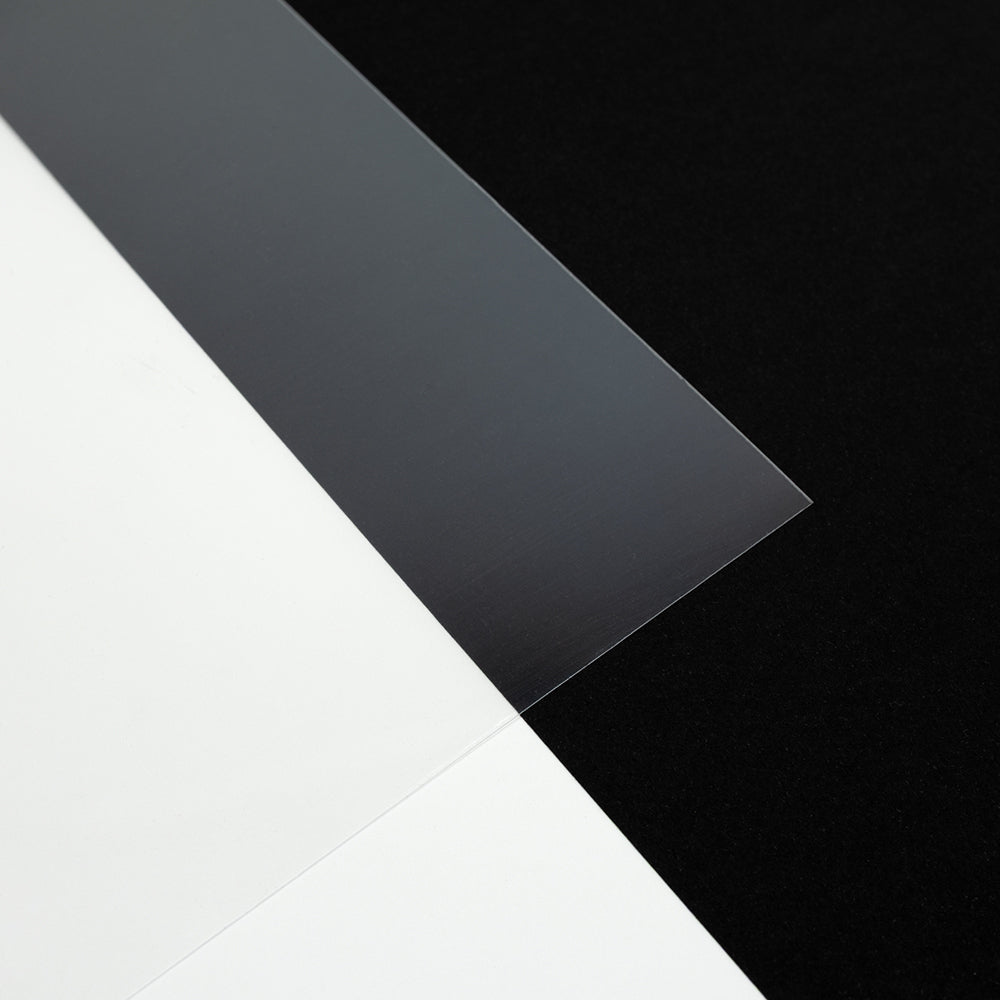 Eine klare Acrylplatte auf schwarz-weißem Hintergrund, die ihre Transparenz und ihre scharfen Kanten zur Geltung bringt – perfekt zum Basteln von Schmuckstücken, beispielsweise zum Gestalten einzigartiger Anhänger mit Schrumpffolie.