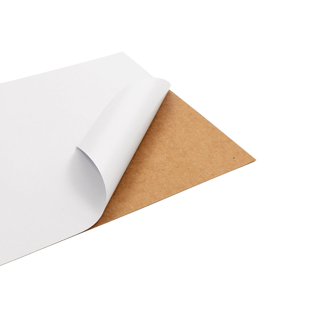 Ein weißes Blatt Papier, ähnlich wie Bastelpapier im A4-Format oder hochwertiges Sticker-Cardstock-Papier, wird teilweise von einem braunen Kartonträger abgezogen.