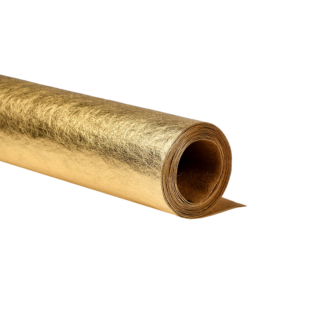 Ein aufgerolltes Blatt goldfarbener Glanzfolie von Alexandra Renke, das an seidenmatt glänzendes Papier erinnert, ruht auf einem weißen Hintergrund.