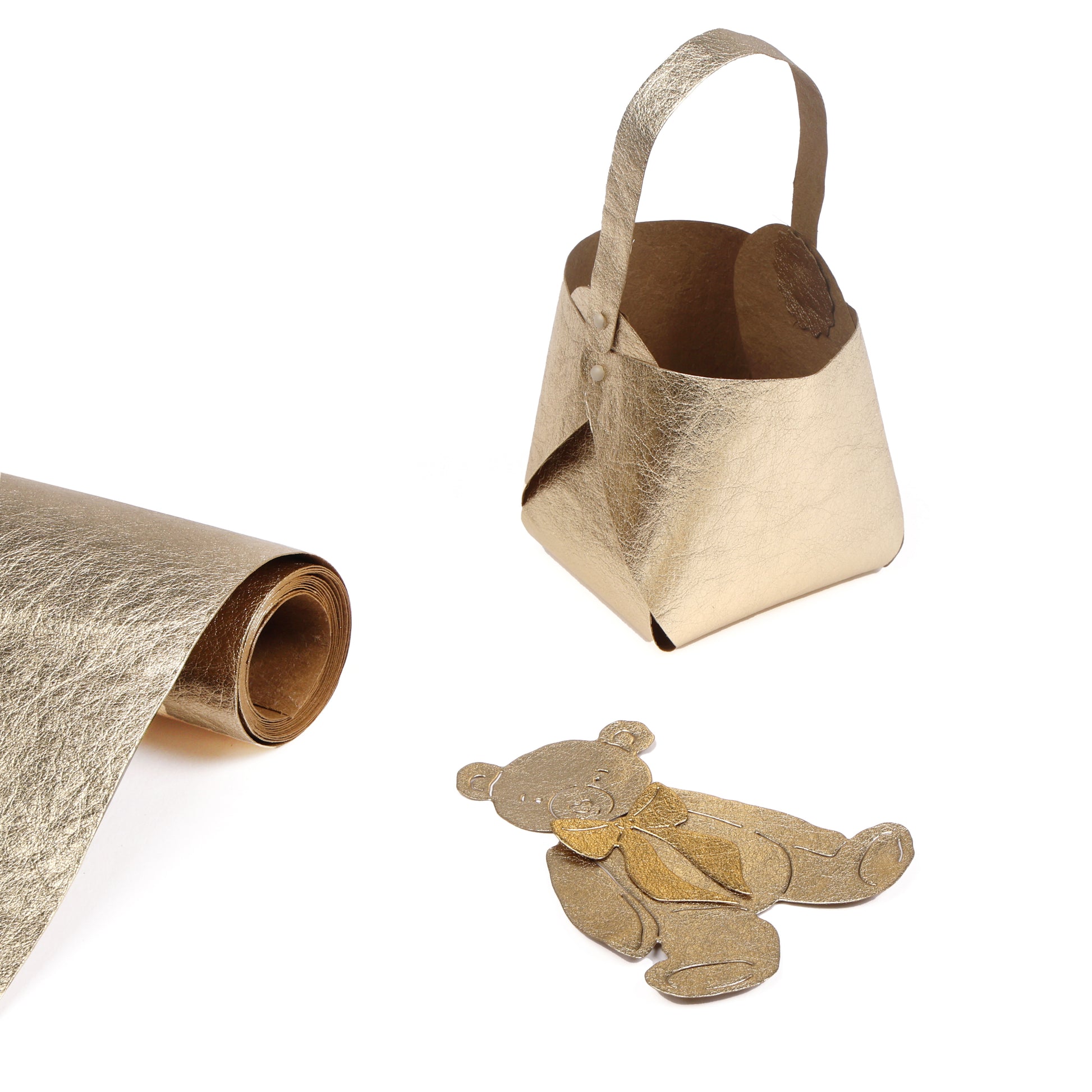 Alexandra Renke goldenes Kunstledertuch, kleine goldene Tasche und goldene Teddybärausschnitte auf weiß - ideal für Buchbinden oder in Kombination mit seidenmatt glänzendem Papier in kreativen Projekten.