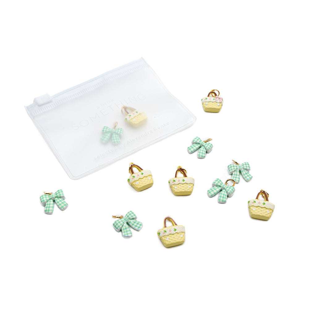 Zehn kleine Anhänger von Alexandra Renke in Form von grünen Schleifen und gelben Körbchen bilden dieses entzückende Anhänger-Set, das zusammen mit einem mattierten Beutel mit Reißverschluss verpackt ist.