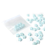 Kleine glasierte Keramikperlen in Sternform von Alexandra Renke sind neben einem transparenten Zip-Beutel auf weißem Hintergrund verstreut-ideal für Schmuck selber machen Projekte.