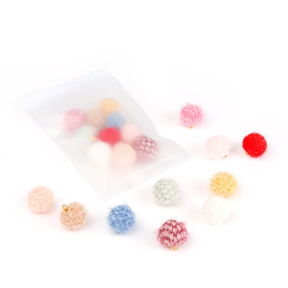 Ambiente farbenfrohe gestrickte Bommelperlen, ideal für Bastelprojekte oder einzigartige Schmuckdesigns, präsentiert in einem halbtransparenten Beutel und verstreut auf weißem Hintergrund.