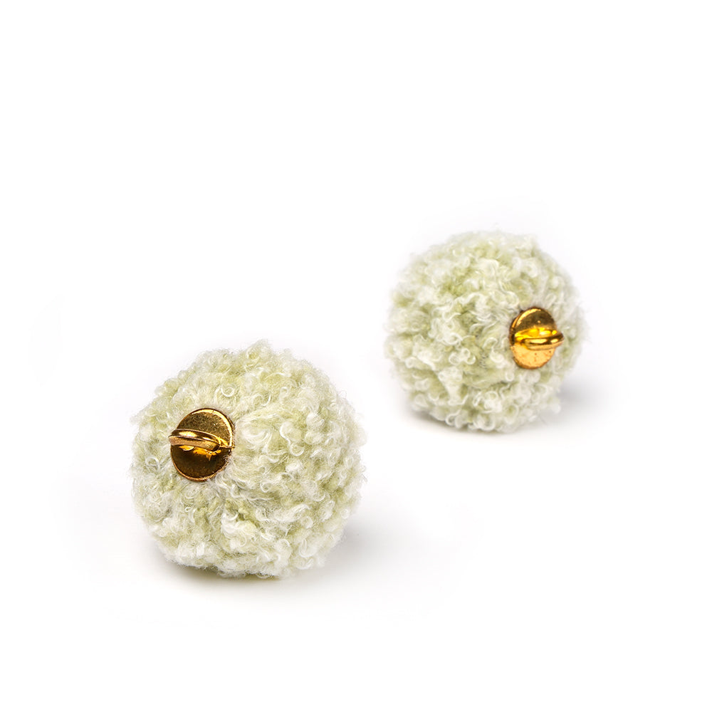 Zwei runde, strukturierte, blassgrüne Ohrringe von Alexandra Renke mit goldenen Metallakzenten und einzigartigen Schmuckdesigns auf weißem Hintergrund.