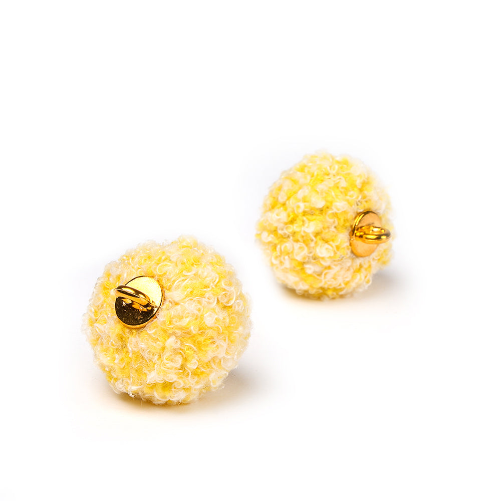 Zwei runde, gelbe, strukturierte Ohrringe von Alexandra Renke mit goldener Rückseite werden auf einem weißen Hintergrund präsentiert - ideal für einzigartige Schmuckdesigns.