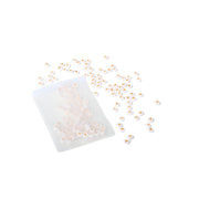 Ein kleines Plastiksäckchen mit winzigen Herzchen Perlen und runden Perlen von ☆, ideal für Schmuck basteln, auf weißem Hintergrund.