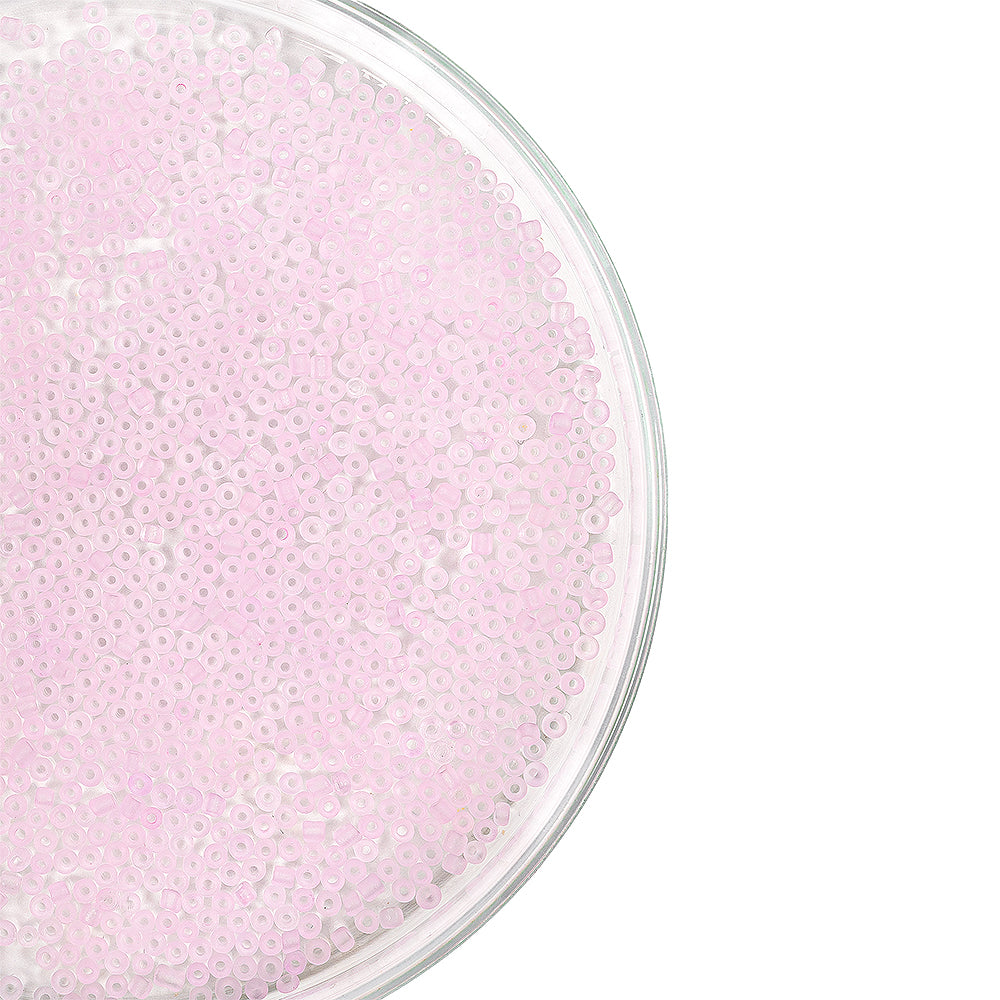 Rosa, durchscheinende Mini-Glasperlen sind in einer durchsichtigen, runden Schale vor weißem Hintergrund verteilt und eignen sich somit perfekt als Bastelzubehör für die Schmuckherstellung und kreative Projekte.